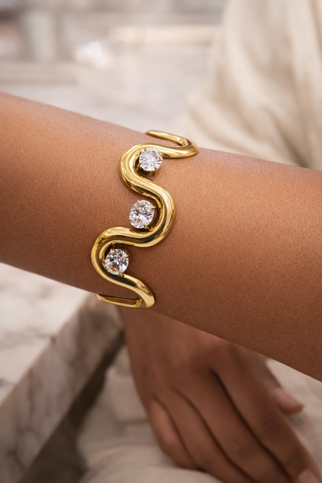 Bracelet NAORA en acier inoxydable doré avec cristaux clairs, design ouvert ondulé, style moderne et élégant