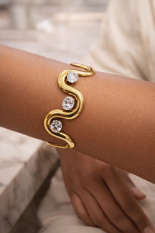 Bracelet NAORA en acier inoxydable doré avec cristaux clairs, design ouvert ondulé, style moderne et élégant